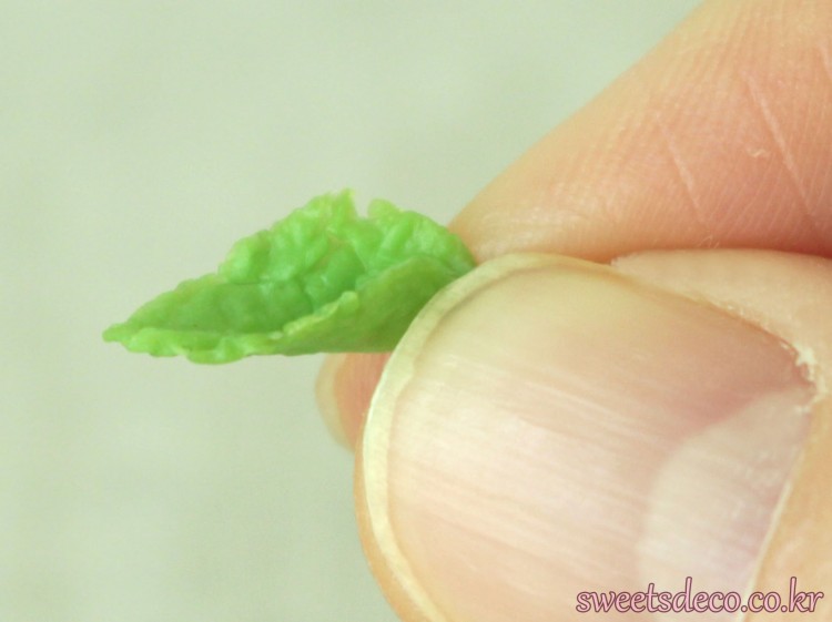 ⑬ 小さい葉2枚は、付け根の部分を親指と人差し指でつまんで立体的にする<br/>※大きい葉はしない